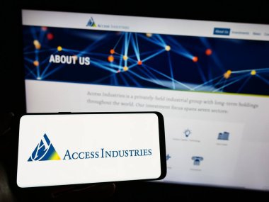 Stuttgart, Germany - 07-08-2023: Person holding smartphone with logo of US holding company Access Industries Inc. on screen in front of website. Focus on phone display. clipart