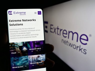 Stuttgart, Almanya - 07-08-2023: ABD 'li ağ şirketi Extreme Networks Inc.' in web sayfası ile cep telefonu tutan kişi logo ile ekranda. Telefon ekranının merkezine odaklan.