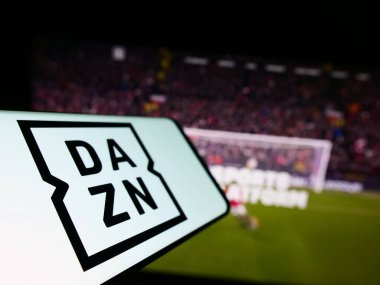 Stuttgart, Almanya - 07-08-2023: İngiliz spor medya şirketi DAZN Group Limited 'in logosuna sahip akıllı telefon iş dünyasının web sitesi önünde ekrana yansıdı. Telefon ekranının soluna odaklan.