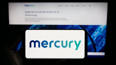 Stuttgart, Almanya - 07-08-2023: ABD 'li savunma şirketi Mercury Systems Inc.' in logosunu elinde tutan kişi web sitesinin önünde ekranda. Telefon ekranına odaklan.