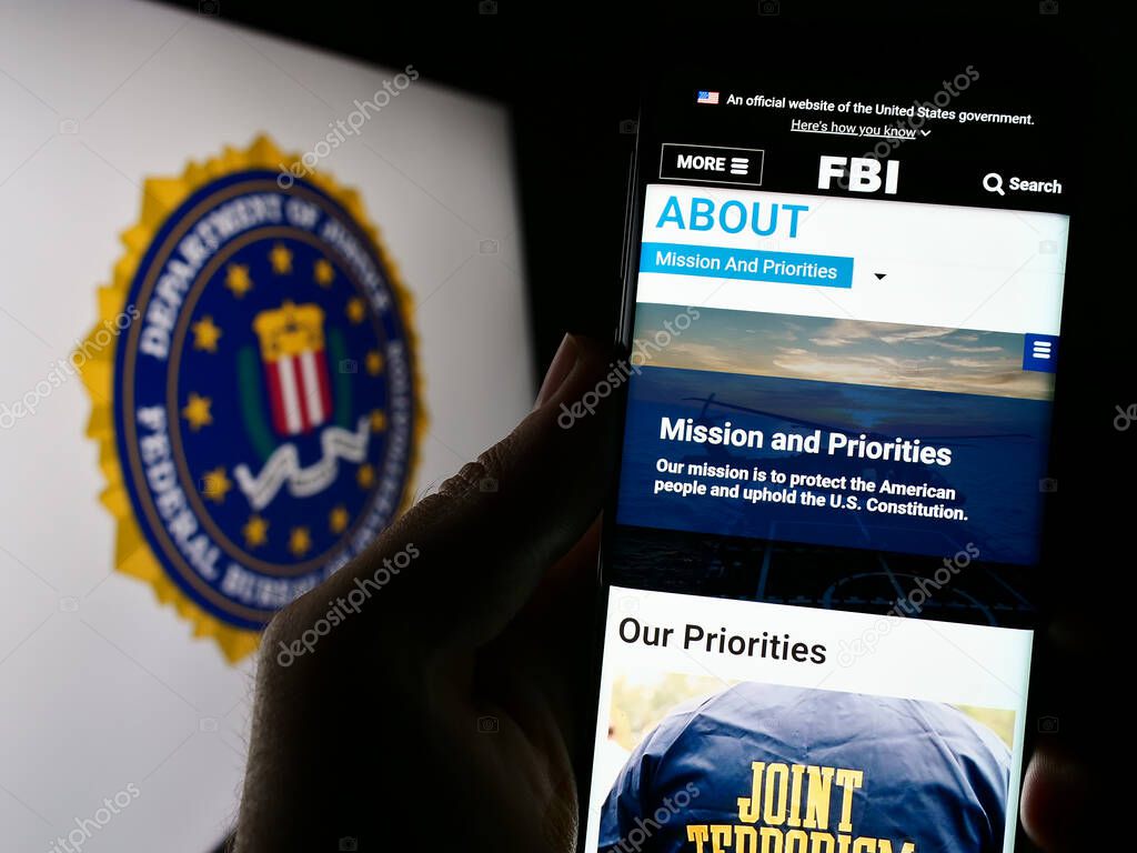 Stuttgart, Germany - 07-09-2023: Person holding cellphone with webpage of US Federal Bureau of Investigation (FBI) on screen in front of seal. Focus on center of phone display.