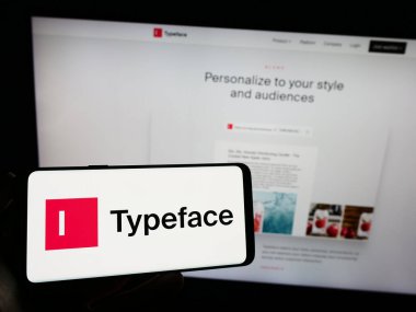 Stuttgart, Almanya - 07-08-2023: Web sayfasının önünde ekranda ABD 'li yapay zeka şirketi Typeface Inc.' in logosuna sahip cep telefonu tutan kişi. Telefon ekranına odaklan.