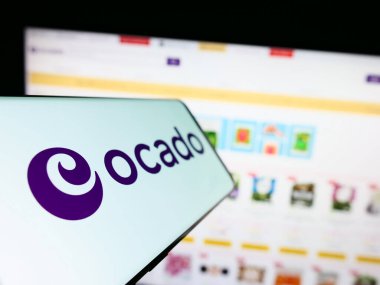 Stuttgart, Almanya - 07-08-2023: İngiliz e-ticaret şirketi Ocado Retail Limited 'in logosuna sahip cep telefonu iş sitesinin önünde ekranda. Telefon ekranının soluna odaklan.