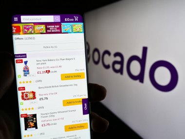 Stuttgart, Almanya - 07-08-2023: İngiliz e-ticaret şirketi Ocado Retail Limited 'in internet sitesiyle cep telefonu tutan kişi logolu ekranda. Telefon ekranının merkezine odaklan.
