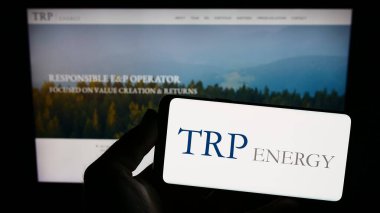 Stuttgart, Almanya - 07-08-2023: İnternet sitesi önünde ekranda ABD 'li petrol ve gaz şirketi TRP Energy LLC' nin logosuna sahip akıllı telefonu tutan kişi. Telefon ekranına odaklan.