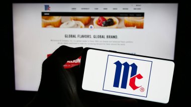 Stuttgart, Almanya - 07-08-2023: ABD 'li McCormick Company Incorporated şirketinin logosuyla cep telefonu sahibi kişi iş sayfasının önünde ekranda. Telefon ekranına odaklan.