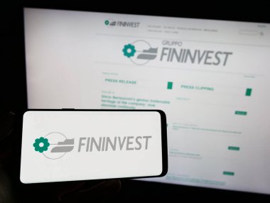 Stuttgart, Almanya - 07-06-2023: İtalyan holding şirketi Fininvest SpA 'nın logosuna sahip cep telefonu sahibi kişi iş sayfasının önünde ekranda. Telefon ekranına odaklan.