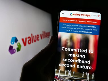 Stuttgart, Almanya - 07-06-2023: Perakende şirketi Value Village 'ın (Savers) web sitesi ile birlikte logo önünde cep telefonu tutan kişi. Telefon ekranının merkezine odaklan.