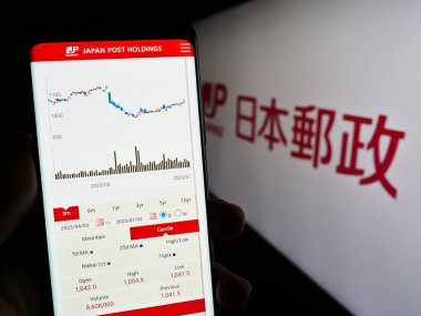 Stuttgart, Almanya - 07-04-2023: Japon şirketi Japan Post Holding Co. Ltd. nin internet sayfası ile akıllı telefon sahibi kişi logo ile ekranda. Telefon ekranının merkezine odaklan.