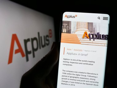 Stuttgart, Almanya - 07-04-2023: İspanyol şirketi Applus Services S.A. 'nın web sitesi ile cep telefonunu logo önünde ekranda tutan kişi. Telefon ekranının merkezine odaklan.