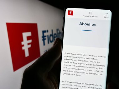 Stuttgart, Almanya - 07-04-2023: Finans şirketi Fidelity International Ltd. 'nin internet sayfası ile cep telefonu tutan kişi logolu ekranda. Telefon ekranının merkezine odaklan.