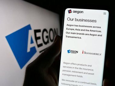 Stuttgart, Almanya - 07-04-2023: Hollandalı finans hizmetleri şirketi Aegon N.V. 'nin web sitesi ile cep telefonunu logo önünde ekranda tutan kişi. Telefon ekranının merkezine odaklan.