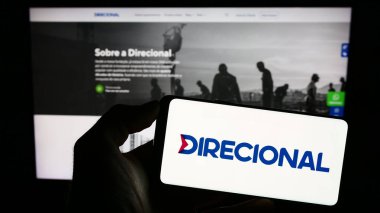 Stuttgart, Almanya - 07-04-2023: İnşaat şirketi Direcional Engenharia S.A. 'nın logosunun bulunduğu akıllı telefonu web sitesinin önünde tutan kişi. Telefon ekranına odaklan.