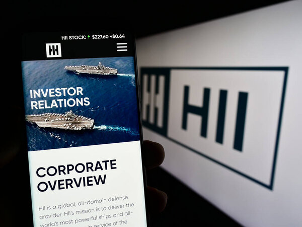 Stuttgart, Germany - 07-02-2023: Person holding cellphone with web page of US shipbuilding company HII Corporate on screen in front of logo. Focus on center of phone display.