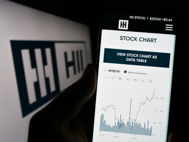 Stuttgart, Almanya - 07-02-2023: ABD 'li tersane şirketi HII Corporate' in web sitesi ile akıllı telefon sahibi kişi logonun önünde ekranda. Telefon ekranının merkezine odaklan.