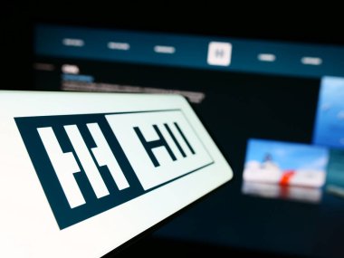 Stuttgart, Almanya - 07-02-2023: Amerikan gemi yapım şirketi HII Corporate 'in logosunu taşıyan cep telefonu iş sitesinin önünde ekranda. Telefon ekranının soluna odaklan.