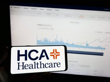 Stuttgart, Almanya - 07-02-2023: Amerikan HCA Healthcare Inc. şirketinin logosunun bulunduğu cep telefonu sahibi kişi iş sayfasının önünde ekranda. Telefon ekranına odaklan.