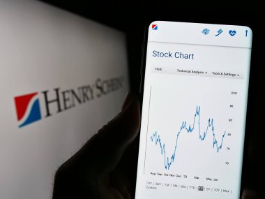 Stuttgart, Almanya - 07-02-2023: ABD 'li sağlık ürünleri şirketi Henry Schein Inc.' in web sayfası ile akıllı telefon sahibi kişi logo ile ekranda. Telefon ekranının merkezine odaklan.