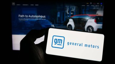 Stuttgart, Almanya - 07-01-2023: Web sayfası önünde ABD 'li otomobil üreticisi General Motors Company' nin (GM) logosunun bulunduğu cep telefonu sahibi kişi. Telefon ekranına odaklan.