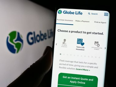 Stuttgart, Almanya - 07-01-2023: ABD 'li sigorta şirketi Globe Life Inc.' in web sitesi ile cep telefonu elinde tutan kişi logonun önünde ekranda. Telefon ekranının merkezine odaklan.