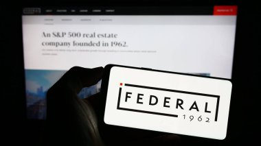 Stuttgart, Almanya - 07-01-2023: İnternet sitesi önünde üzerinde Federal Emlak Yatırım Vakfı logosu bulunan akıllı telefon sahibi kişi. Telefon ekranına odaklan.