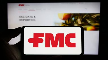 Stuttgart, Almanya - 07-01-2023: ABD 'li kimya şirketi FMC Corporation' ın logosuyla cep telefonu sahibi kişi iş sayfasının önünde ekranda. Telefon ekranına odaklan.