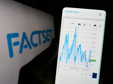 Stuttgart, Almanya - 07-01-2023: ABD 'li şirket FactSet Research Systems Inc.' in web sitesi ile cep telefonu tutan kişi logo önünde ekranda. Telefon ekranının merkezine odaklan.