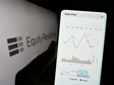 Stuttgart, Almanya - 07-01-2023: ABD 'li emlak şirketi Equity Residential' in web sitesi ile birlikte logo önünde cep telefonu tutan kişi. Telefon ekranının merkezine odaklan.