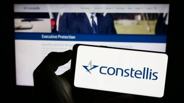 Stuttgart, Almanya - 07-01-2023: ABD 'li güvenlik şirketi Constellis Holding LLC' nin logosuyla cep telefonu sahibi kişi iş sayfasının önünde ekranda görülüyor. Telefon ekranına odaklan.