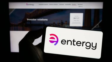 Stuttgart, Almanya - 07-01-2023: ABD 'li enerji şirketi Entergy Corporation' ın logosuyla cep telefonu sahibi kişi iş sayfasının önünde ekranda. Telefon ekranına odaklan.