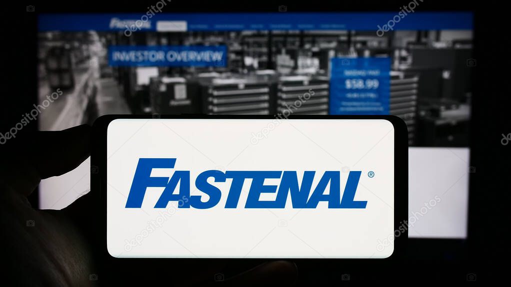Stuttgart, Germany - 07-01-2023: Person holding smartphone with logo of US distribution business Fastenal Company on screen in front of website. Focus on phone display.