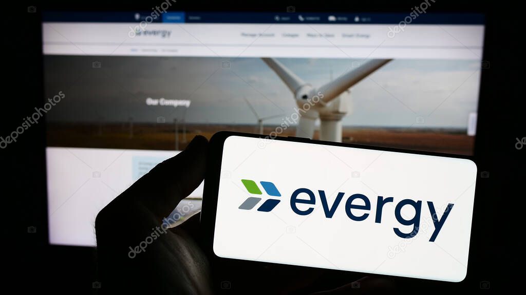 Stuttgart, Germany - 07-01-2023: Person holding smartphone with logo of US utility company Evergy Inc. on screen in front of website. Focus on phone display.
