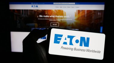 Stuttgart, Almanya - 07-01-2023: Elektrik idaresi şirketi Eaton Corporation plc 'in logosunun bulunduğu akıllı telefonu web sitesinin önünde tutan kişi. Telefon ekranına odaklan.