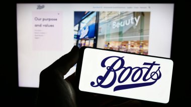 Stuttgart, Almanya - 07-01-2023: İngiliz eczane şirketi Boots UK Limited 'in logosuna sahip akıllı telefon sahibi kişi web sitesinin önünde ekranda. Telefon ekranına odaklan.