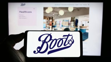 Stuttgart, Almanya - 07-01-2023: İngiliz eczane şirketi Boots UK Limited 'in logosuyla cep telefonu sahibi kişi iş sayfasının önünde ekranda görülüyor. Telefon ekranına odaklan.