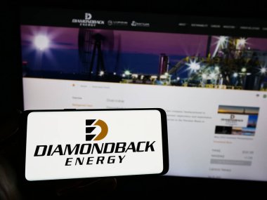 Stuttgart, Almanya - 06-30-2023: ABD 'li petrol ve doğalgaz şirketi Diamondback Energy Inc.' in logosunu elinde tutan kişi web sitesinin önünde ekranda. Telefon ekranına odaklan.