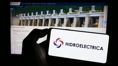 Stuttgart, Almanya - 06-30-2023: Romen enerji kuruluşu Hidroelectrica SA 'nın logosuyla cep telefonu sahibi kişi iş sayfasının önünde ekranda görülüyor. Telefon ekranına odaklan.