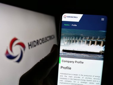 Stuttgart, Almanya - 06-30-2023: Romen enerji kuruluşu Hidroelectrica S.A. 'nın İnternet sayfası ile cep telefonu tutan kişi logonun önünde ekranda görülüyor. Telefon ekranının merkezine odaklan.