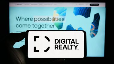 Stuttgart, Almanya - 06-28-2023: Web sayfası önünde ekranda ABD 'li veri merkezi şirketi Digital Realty Trust Inc.' in logosunun bulunduğu cep telefonu sahibi kişi. Telefon ekranına odaklan.
