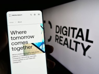 Stuttgart, Almanya - 06-28-2023: Veri merkezi şirketi Digital Realty Trust Inc. 'in web sitesi ile cep telefonunu elinde tutan kişi logolu ekranda. Telefon ekranının merkezine odaklan.