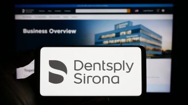 Stuttgart, Almanya - 06-28-2023: ABD 'li diş donanım şirketi Dentsply Sirona Inc.' in logosunu taşıyan kişi web sitesinin önünde ekranda. Telefon ekranına odaklan.