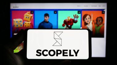 Stuttgart, Almanya - 06-28-2023: ABD 'li video oyunları şirketi Scopely Inc.' in logosunu elinde tutan kişi web sitesinin önünde ekranda. Telefon ekranına odaklan.