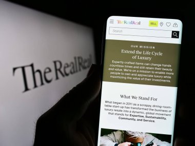 Stuttgart, Almanya - 06-28-2023: ABD 'li e-ticaret şirketi The RealReal Inc.' in web sayfası olan cep telefonu logonun önünde ekranda. Telefon ekranının merkezine odaklan.