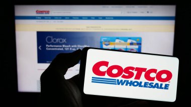 Stuttgart, Almanya - 06-28-2023: ABD 'li Costco Wholesale Corporation şirketinin logosunu elinde tutan kişi web sitesinin önünde ekranda. Telefon ekranına odaklan.
