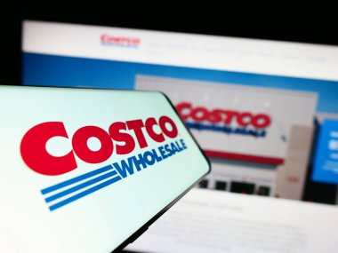 Stuttgart, Almanya - 06-28-2023: Web sitesinin önünde ekranda Costco Toptan Şirketi logosu olan akıllı telefon. Telefon ekranının merkez soluna odaklan.