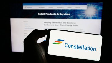 Stuttgart, Almanya - 06-25-2023: ABD 'li Constellation Energy Corporation şirketinin logosunu elinde tutan kişi web sitesinin önünde ekranda. Telefon ekranına odaklan.