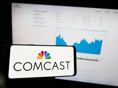 Stuttgart, Almanya - 06-25-2023: ABD telekomünikasyon şirketi Comcast Corporation 'ın logosunun bulunduğu cep telefonu web sayfası önünde ekranda. Telefon ekranına odaklan.