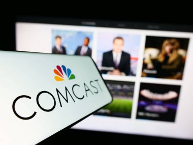Stuttgart, Almanya - 06-25-2023: İnternet sitesinin önünde ekranda Amerikan telekomünikasyon şirketi Comcast Corporation 'ın logosunun bulunduğu cep telefonu. Telefon ekranının soluna odaklan.