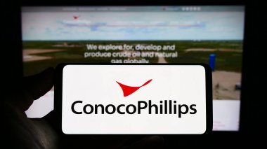 Stuttgart, Almanya - 06-25-2023: İnternet sitesi önünde ABD petrol ve doğalgaz şirketi ConocoPhillips Company logosu olan akıllı telefon sahibi kişi. Telefon ekranına odaklan.