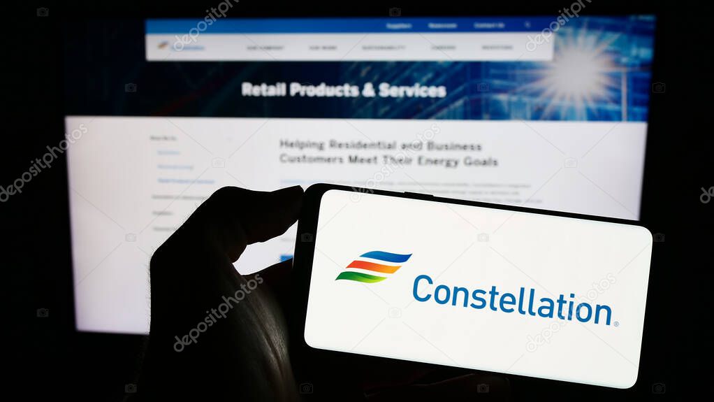 Stuttgart, Germany - 06-25-2023: Person holding smartphone with logo of US company Constellation Energy Corporation on screen in front of website. Focus on phone display.